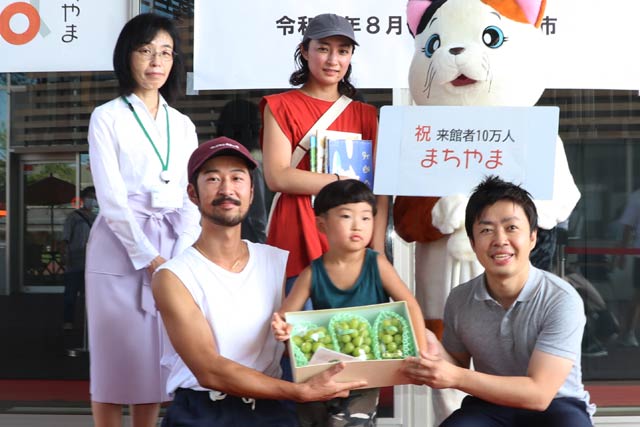 「まちやま」来館者10万人目になった清水さん家族と滝沢市長、篠原図書館長、えんがわにゃんこ