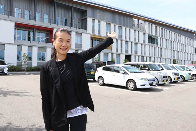 プロジェクションマッピングを映す三条市立大学の壁面を背に25周年記念事業実行委員会の吉田加奈子実行委員長