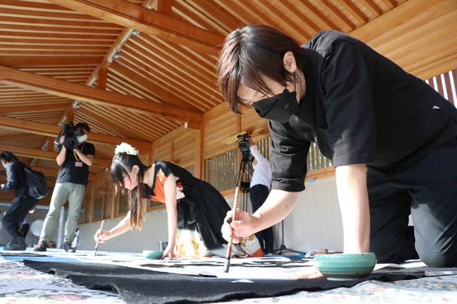 奉納揮毫する下田彩水さん(左)と下田逅絆さん