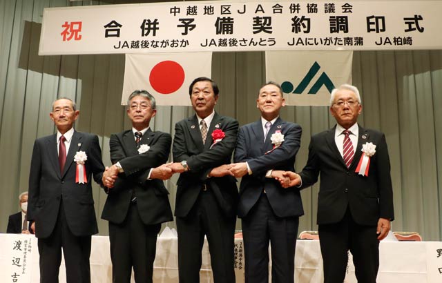 合併予備契約調印式で調印して握手する左からJA柏崎の渡辺吉隆氏、JAにいがた南蒲の吉田文彦氏、JA新潟中央会の伊藤能徳代表理事会長、JA越後さんとうの奈良場義夫氏、JA越後ながおかの野口剛氏