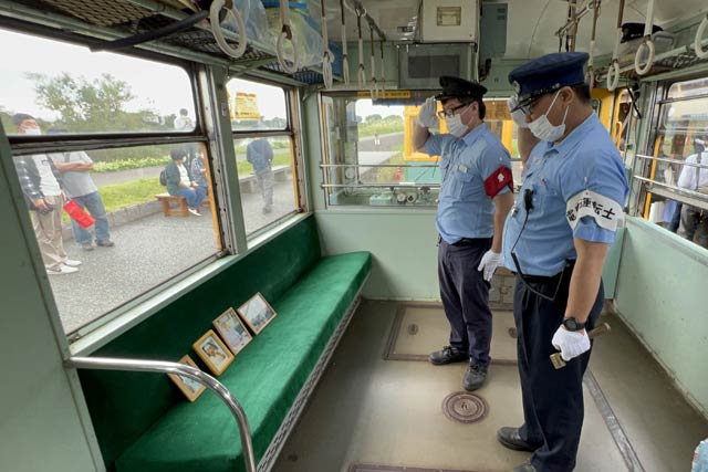 一番列車にのせたかぼちゃ電車の保存に貢献した4人の遺影と運行後に敬礼する会員、右から2人目が燕市の写真家の捧武さん