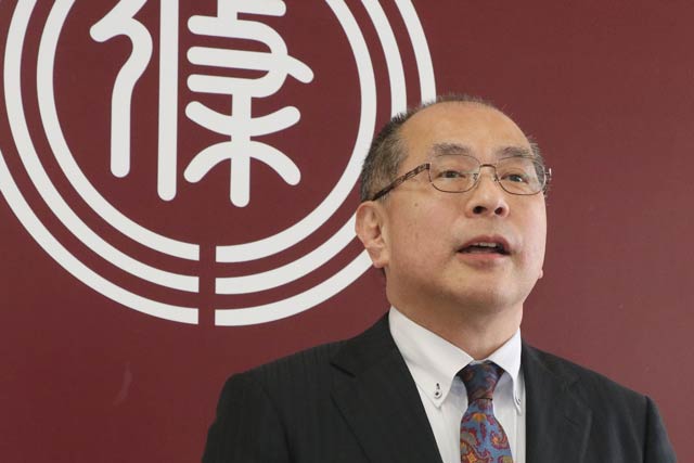 退任式で市旗を背にあいさつする若山副市長