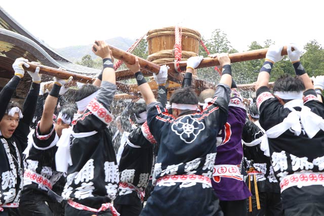 弥彦神社拝殿前で神湯を入れたたるみこしをもむ