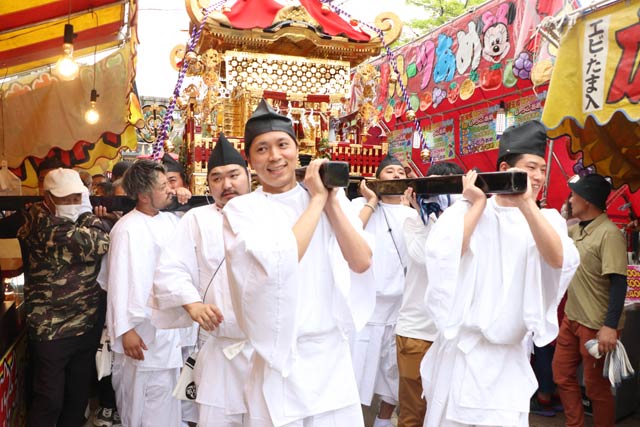 露店をよけながら参道を進む神輿