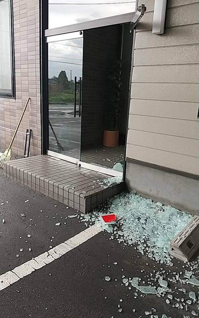 突風でガラスが粉々に割れた小柳産業事務所の入り口ドア