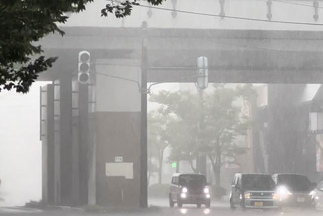 燕三条駅前の信号機が停電し暗くなって車のヘッドライトが点灯、景色が雨でかすむ