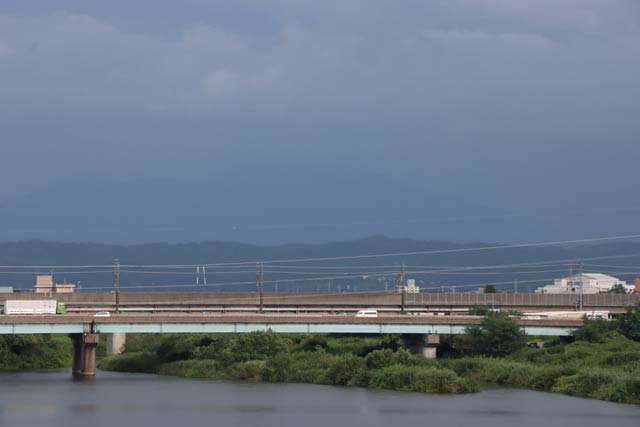 燕市の朝日大橋上からは降雨のためか粟ヶ岳の稜線がかすんでほとんど見えない（17日午後4時ごろ）