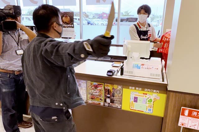ナイフを手に従業員を脅す犯人役