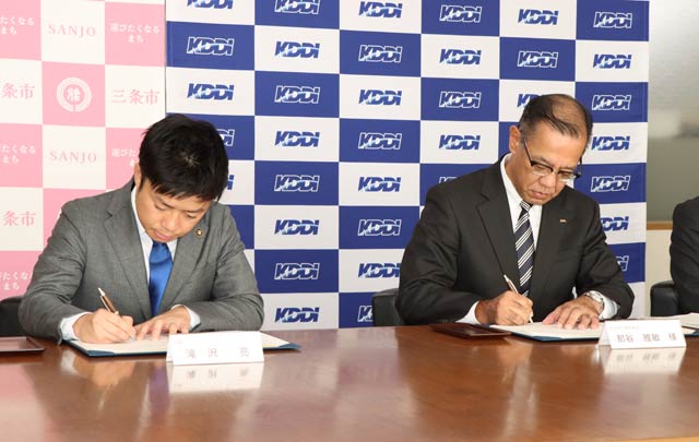 包括連携協定に署名する滝沢市長(左)とKDDIソリューション事業本部・ビジネスデザイン本部の那谷本部長