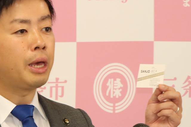 定例記者会見で自身の名刺を見せる滝沢市長
