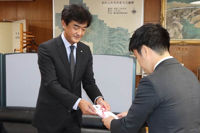 滝沢市長(右)に目録を手渡すセイヒョーの飯塚社長