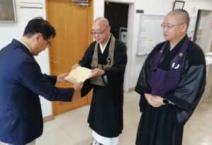 下田仏教会の松井会長から三条社協の笹川事務局長に托鉢の浄財15万8700円を手渡す