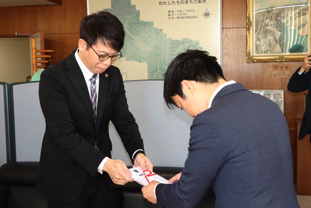 滝沢市長に寄付目録を手渡す樋口社長