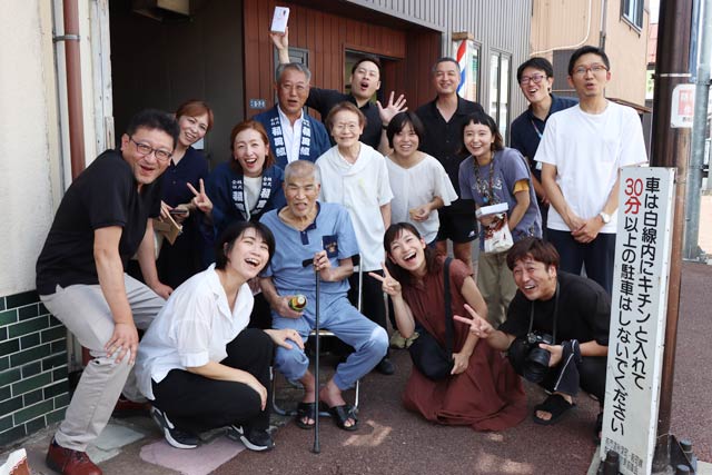 上棟祝い式で店の前に出てきた小林榮一さんと一緒に写真に写りたいと集まった人たち。いかに小林榮一さんが多くの人たちに愛されてきたかわかる