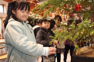 「道の駅たがみ」でクリスマスツリーにオーナメントを飾る田上いずみルーテル幼稚園の年長児