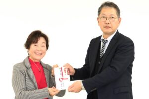 燕市社協の小越会長(左)に寄付を手渡す白根ガスの佐藤取締役