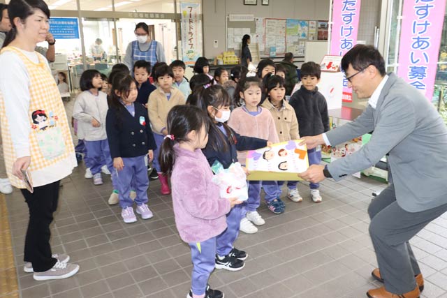 三条市社協の笹川事務局長に赤い羽根共同募金への寄付を手渡すきらきら保育園年長児