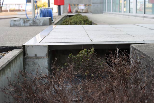 地震の揺れで溝に渡したパネルが跳ね上がり建物が溝の空間を使って揺れる