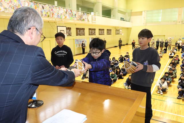 燕市教委の長学校教育課長から児童にグローブを手渡す