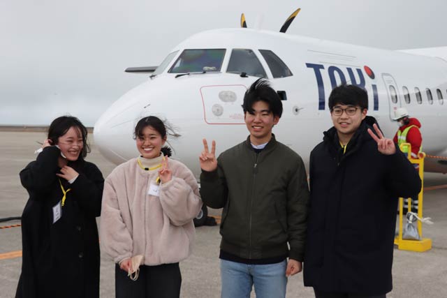 着陸したトキエアの機体の前で「燕市役所まちあそび部」の高校生4人