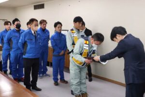 応援隊に「災害応援隊」とあるマグネットシートを手渡す滝沢市長