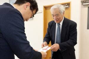 石川県共同募金会への10万円の寄付を手渡す中新自治会の白椿会長(右)