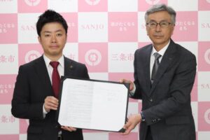 包括連携協定の協定書を手に滝沢市長(左)と坂井社長