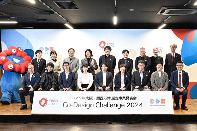 大阪・関西万博選定事業発表会で後列左から4人目がドッツアンドラインズの斎藤代表