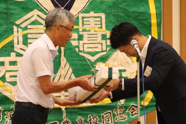 野球部の倉繁監督(左)に甲子園出場主将の池田さんから新規格の低反発バットを手渡す