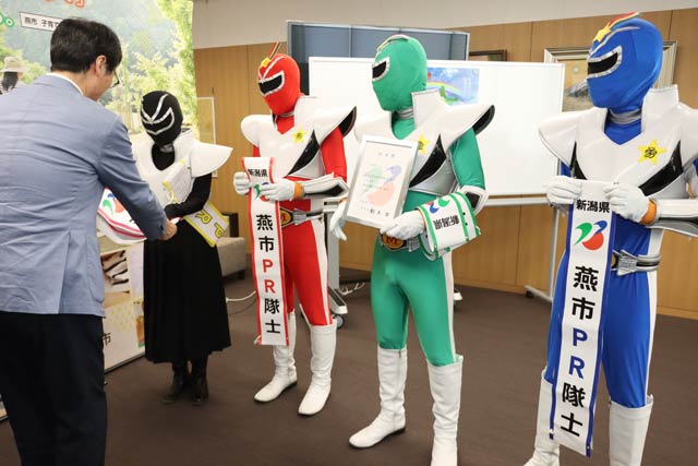鈴木市長から任命書、たすき、名刺を手渡す