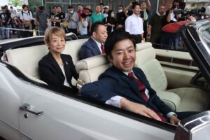 「まちやま」でジャイアント馬場さんの愛車キャデラックに乗り込んでパレードに出発する滝沢市長とジャイアント馬場さんのめいの緒方理咲子さん