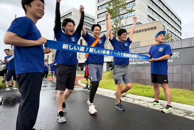 オレンジのたすきをかけた最終ランナー笹川次年度会長ら会員3人が手をつないで新潟県央基幹病院にゴール