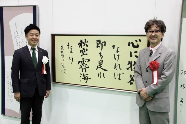 書道部門に漢字仮名交じり作品「物欲はないが…」を出品した滝沢市長(左)と書道部門審査員の山田修也さん