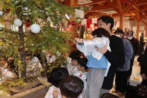道の駅たがみが設置したクリスマスツリーにオーナメントを下げる田上いずみルーテル幼稚園園児