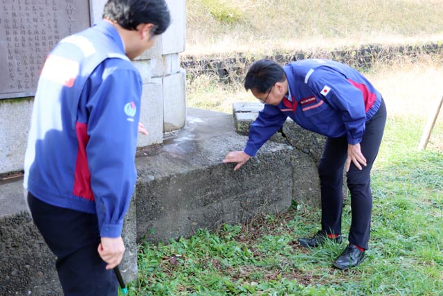 でおよそ100年以上前に建設された自在堰の一部が使われた信濃川補修工事竣工記念碑の台座にふれる