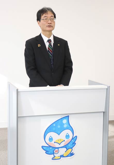 水道局キャラクター「つばひこ君」を張った演台を前にあいさつする鈴木市長