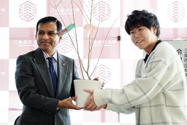 サルするバリをシャハリアル学長に手渡す須貝さん