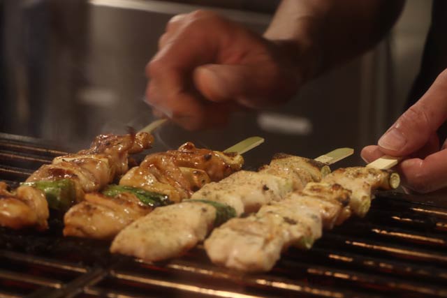 オープンキッチンで焼き鳥を焼く