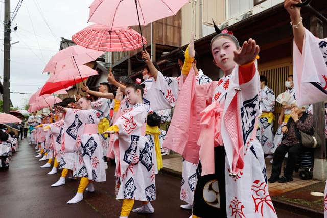 花柳流師匠の家の前でピンクの傘をさしかけてもらって「伊勢音頭」を踊る踊り子