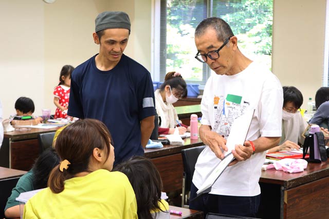 自身のスケッチブックを見せる松岡さん
