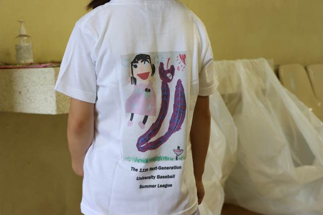 背中に滝沢さんの作品がプリントされたTシャツを着て始球式