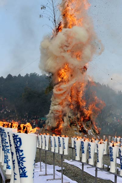 奉納された和ろうそくの火が揺れ塞の神が燃え盛る
