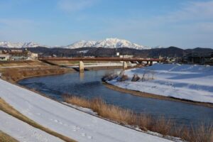 三条市を流れる五十嵐川の堤外地は日が当たる北側の左の堤防の雪は溶け、南側の右の堤防は雪に覆われたまま