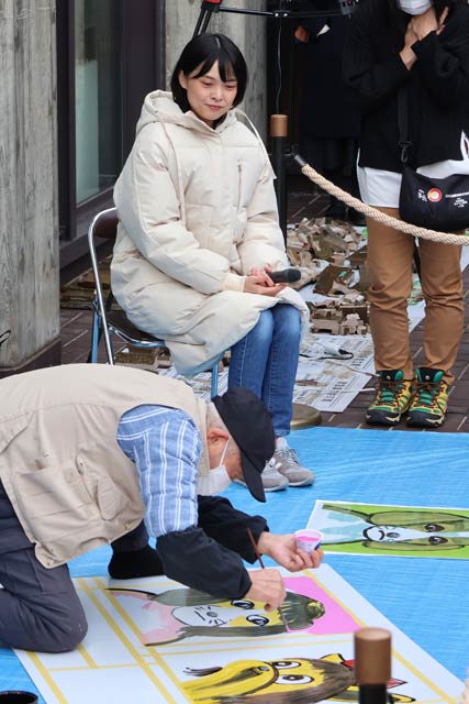 松田ペットの看板絵師、青柳謙一さんの制作のようすを見守るKaedeさん