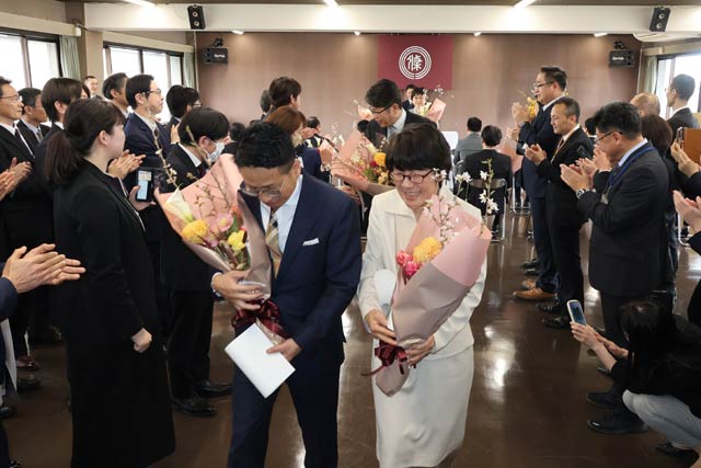 職員の拍手に送られる退職者