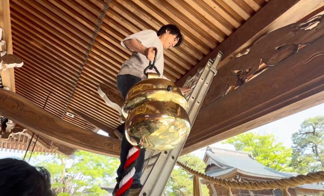 白井さんが自分で磨いた鈴を自分で拝殿に下げる