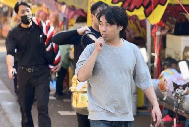 露店が並ぶ参道を鈴を担いで進む