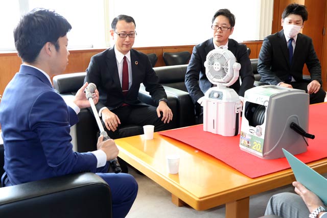 寄贈したポータブル電動ミストファンと20mの園芸ホースリールを前に