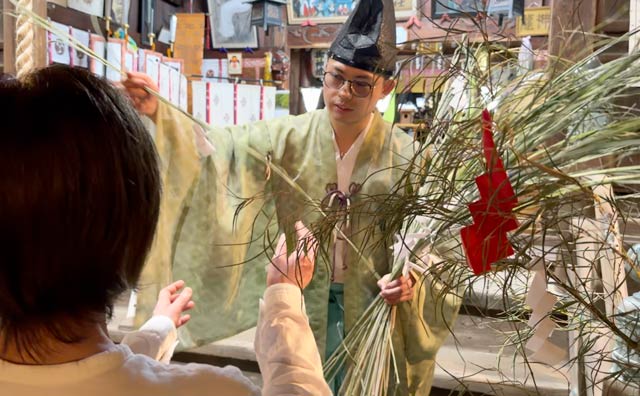 参拝者に紙垂（しで）付きの萱とせんべいの授与