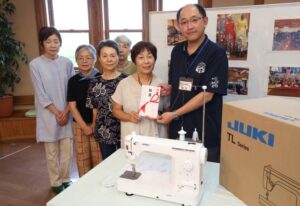 「環境すまいる広場」の島田代表からかんきょう庵の坂田館長に目録を手渡す